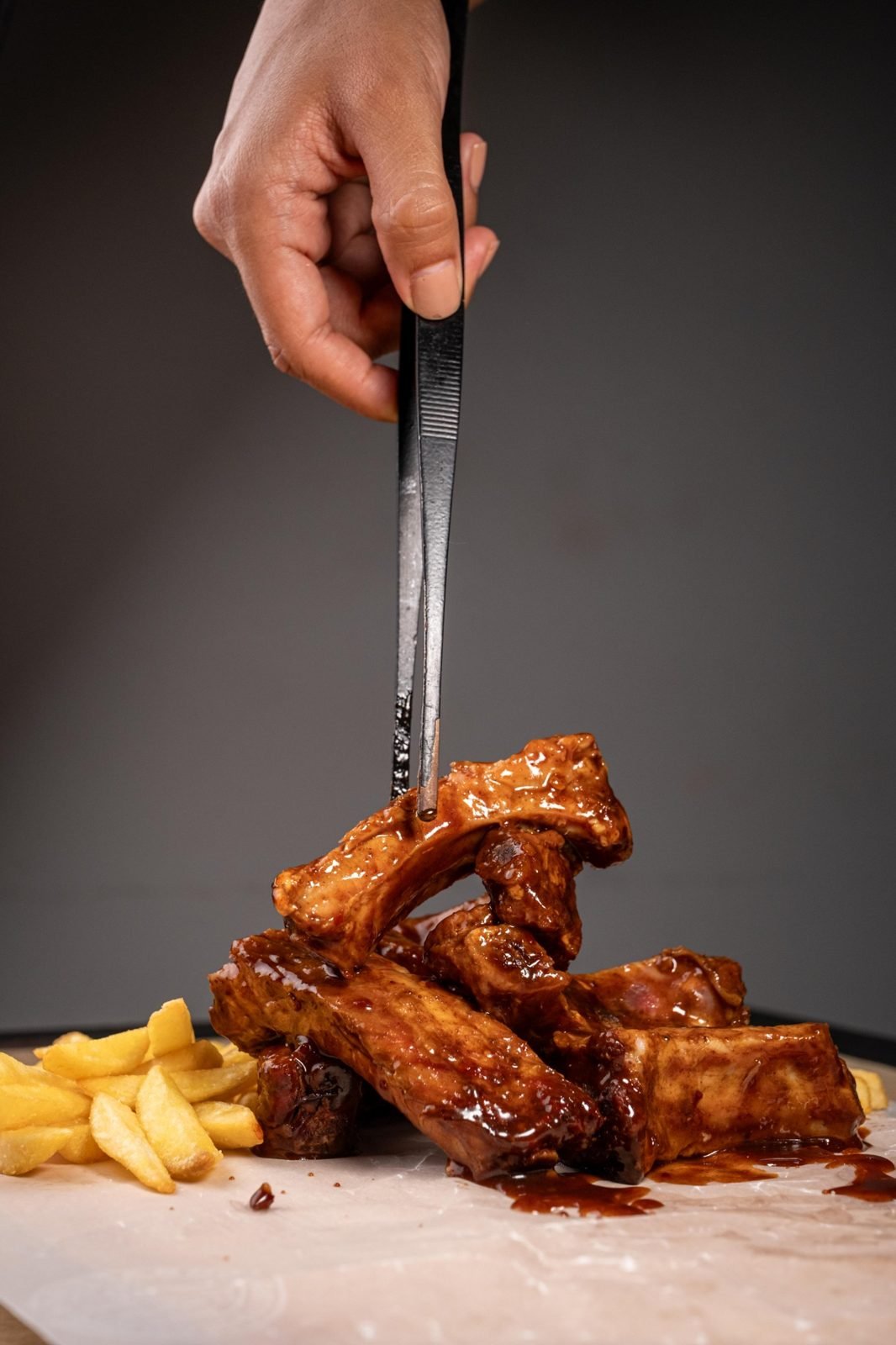 Costillas BBQ con papas, servidas con pinza